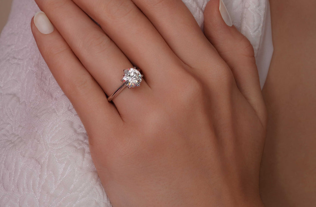 Hand wearing a diamond ring with a soft background